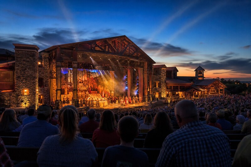 Large Branson theater production with a warm stage, sweeping lights, and an audience at dusk