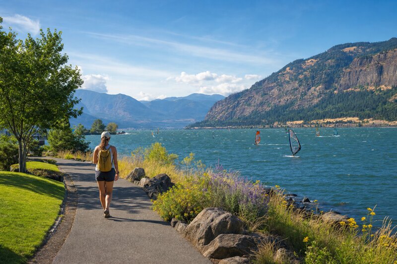 Contextual illustration of a Hood River waterfront path beside windsurfers on the Columbia River