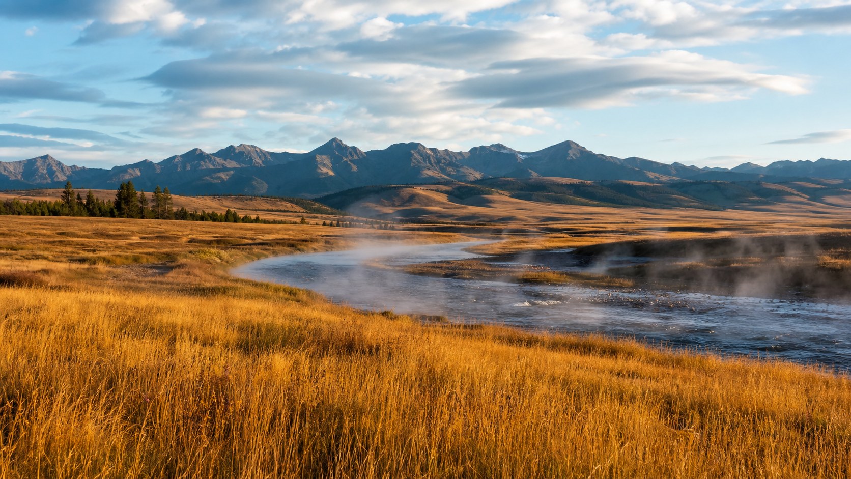Golden Yellowstone valley with river steam and distant mountains